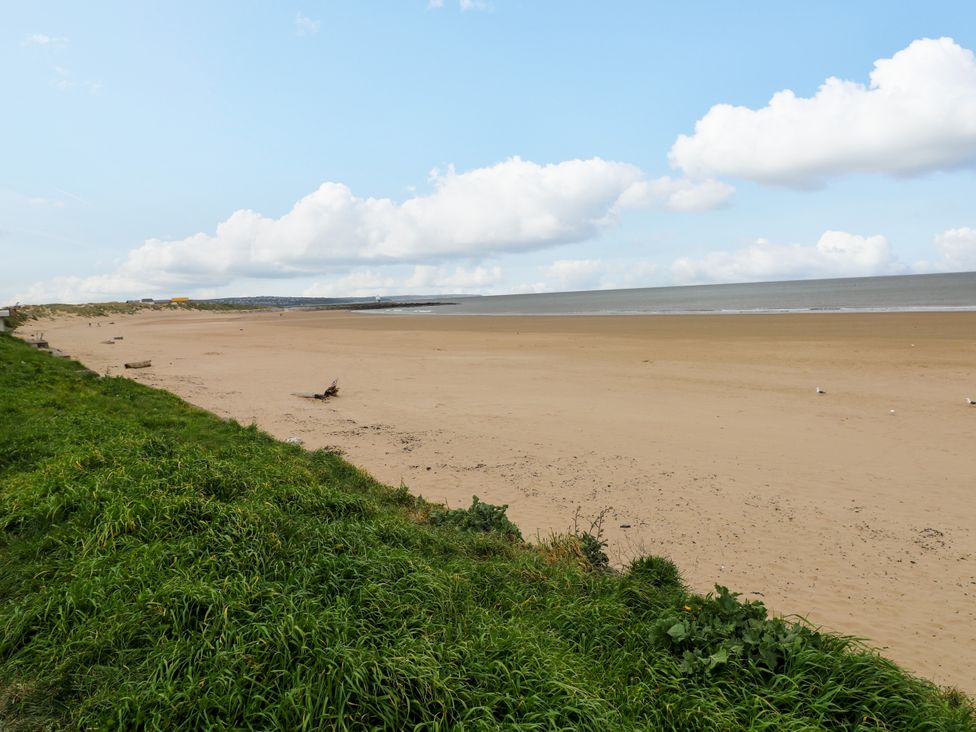 A beach with sand and grass at The Bungalow in Porthcawl