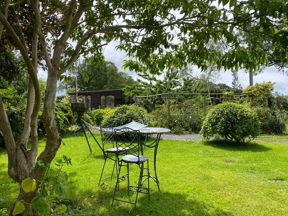 A garden with a table and chairs surrounded by greenery at Cefn Campstone Llanvihangel Crucorney near Abergavenny