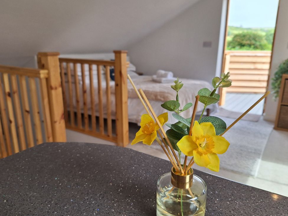 A bedroom with a bed and flowers on a table at The Halt in Maiden Newton
