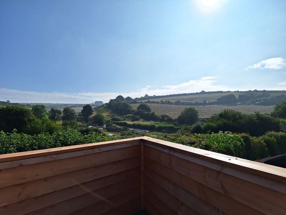A view of hills and trees from a wooden railing at The Halt in Maiden Newton