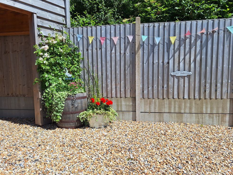 An outdoor area with flowers and a sign that reads guest parking at The Halt in Maiden Newton