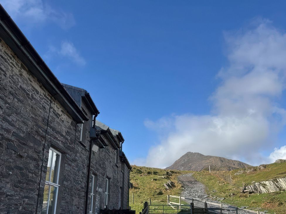 A view of a stone building and pathway leading to a mountain at Ty Llugwy in Capel Curig near Betws-Y-Coed