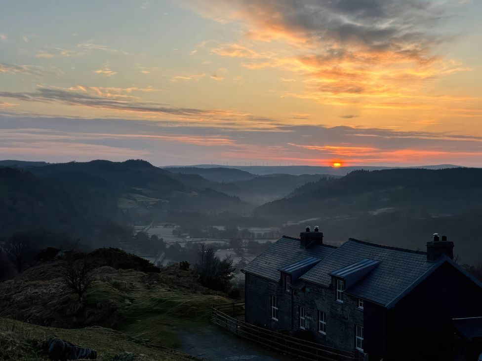 A sunrise view with mountains and a house at Ty Llugwy in Capel Curig near Betws-Y-Coed