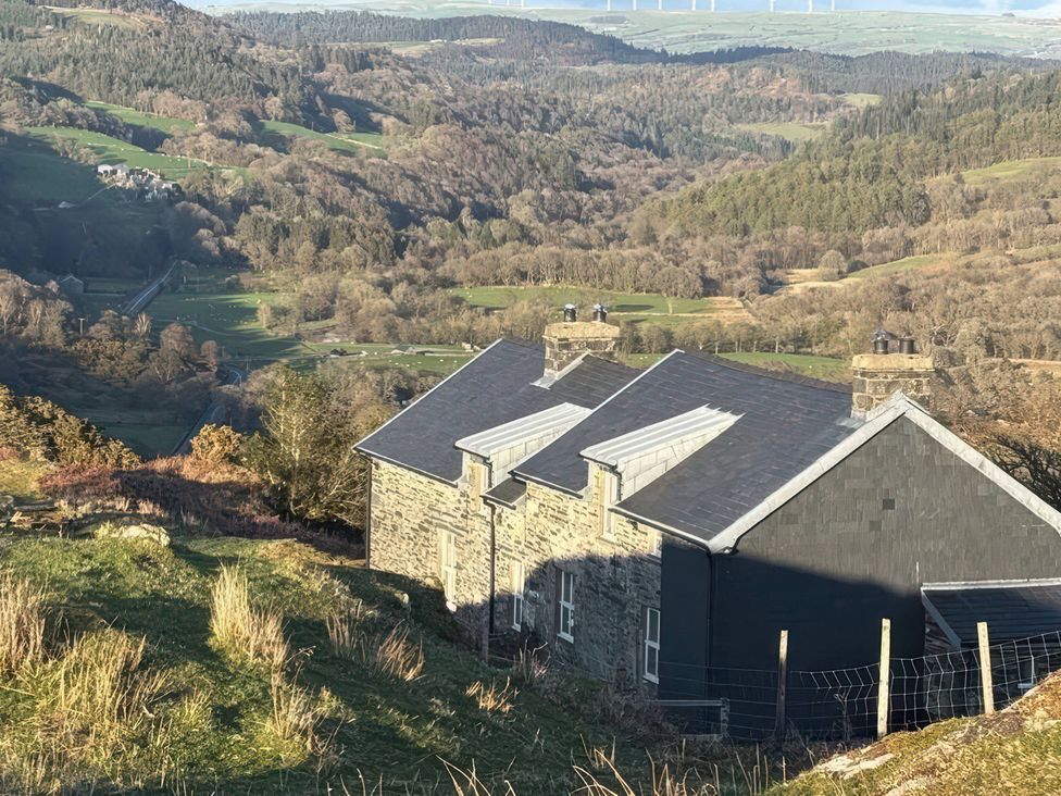 A house on a hillside with a view of the landscape at Ty Siabod in Capel Curig near Betws-Y-Coed