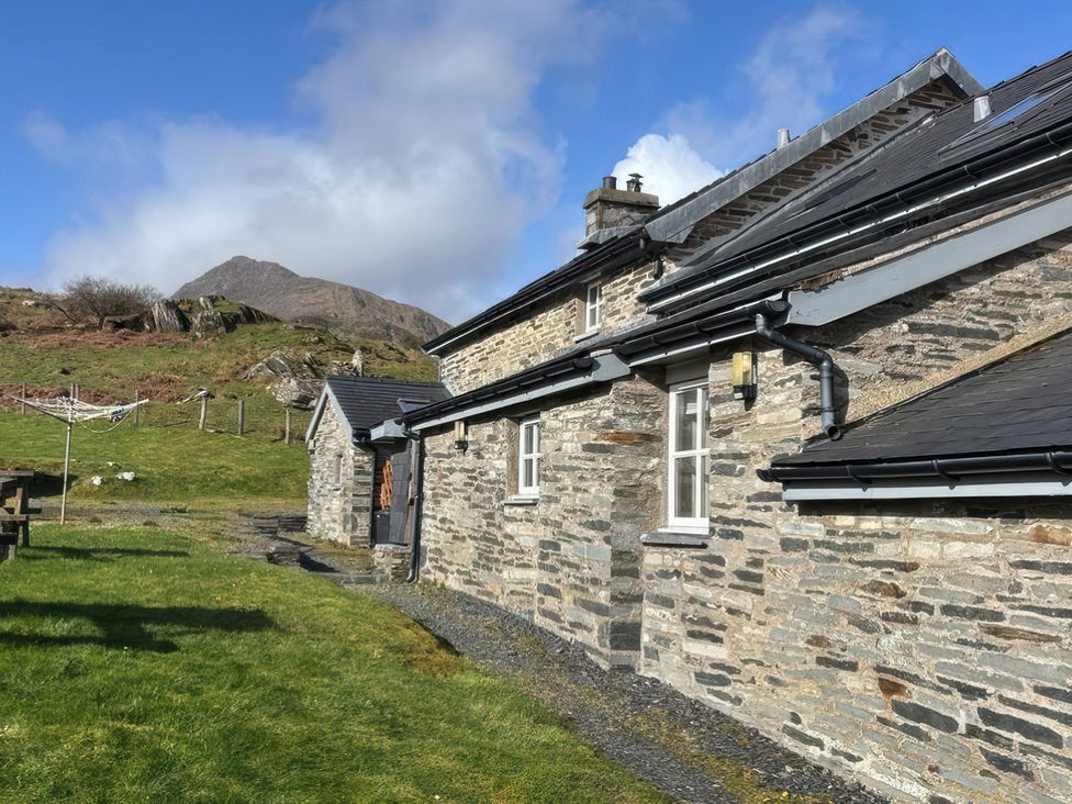 A stone house with a mountain in the background at Ty Siabod in Capel Curig near Betws-Y-Coed