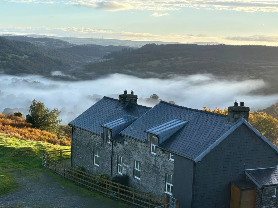 A house in a hilly landscape with fog at Ty Siabod in Capel Curig near Betws-Y-Coed