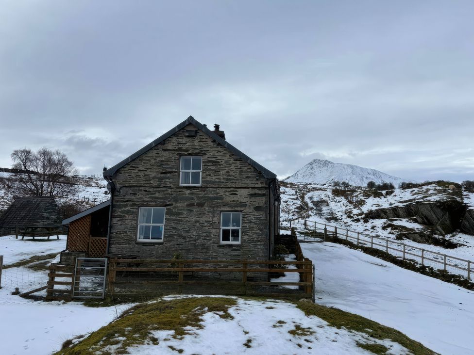A house surrounded by snow with mountains in the background at Ty Llewelyn in Capel Curig near Betws-Y-Coed