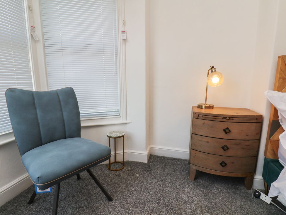 A bedroom with a chair and a side table with a lamp at 174 High Street in Marske-By-The-Sea