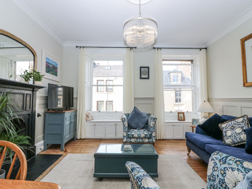 A living room with a sofa and television at 11A High Street in Jedburgh