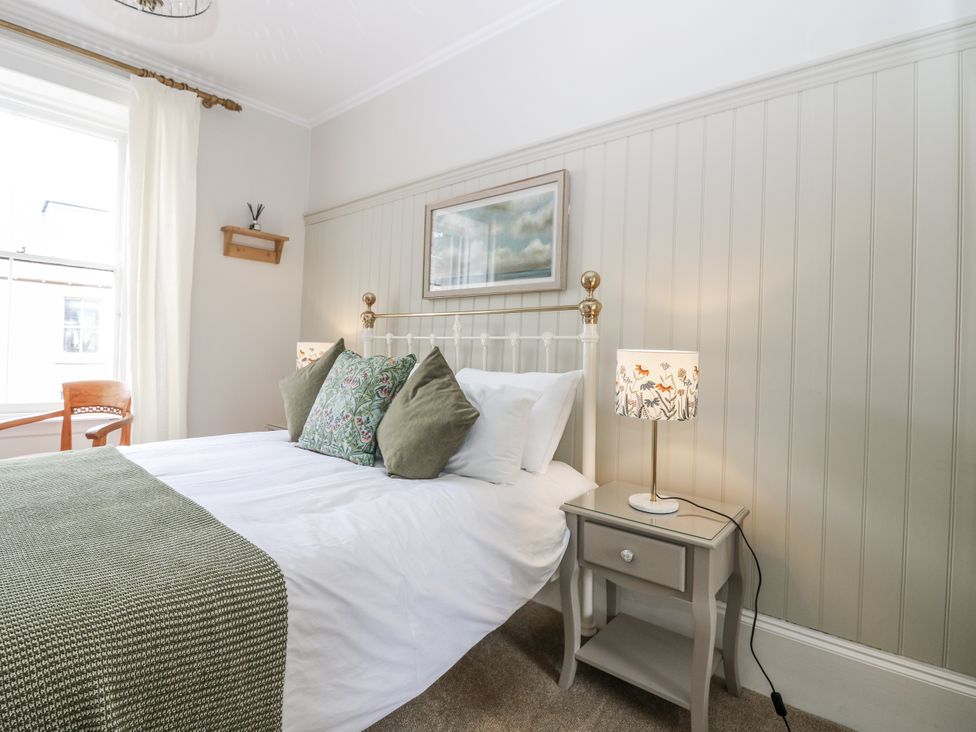 A bedroom with a bed, side table, lamp and chair at 11A High Street in Jedburgh