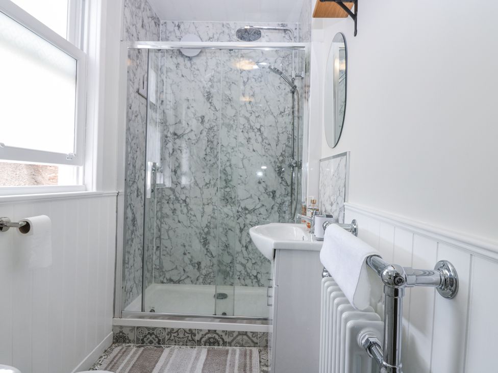 A bathroom with a shower, sink, and towel rack at 11A High Street, Jedburgh