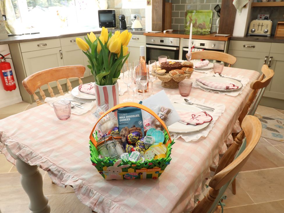 A kitchen with a dining table set with tulips and a basket of treats at The Museum in Nenthead