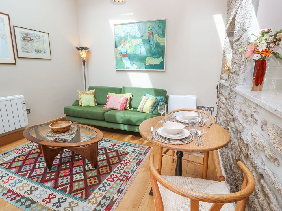A living room with a green sofa and dining table at The Stables in St Just