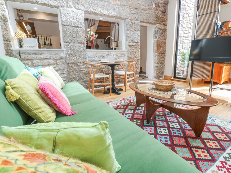 A living room with a green sofa and coffee table at The Stables in St Just