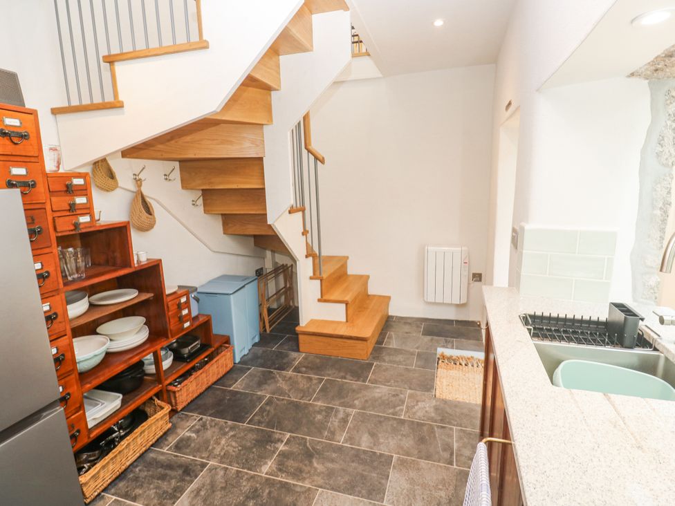 A kitchen with a staircase and wooden shelves at The Stables in St Just