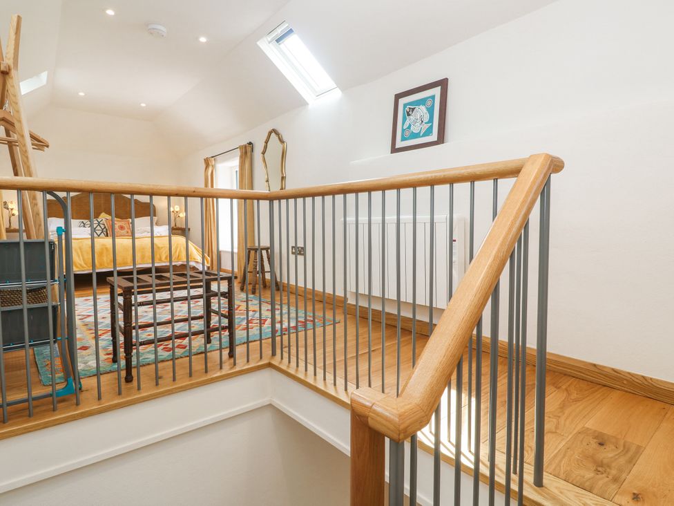 A bedroom with a bed, table, and artwork at The Stables St Just
