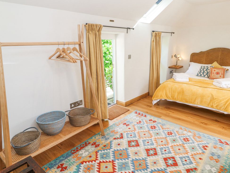 A bedroom with a bed and hanging rack at The Stables in St Just