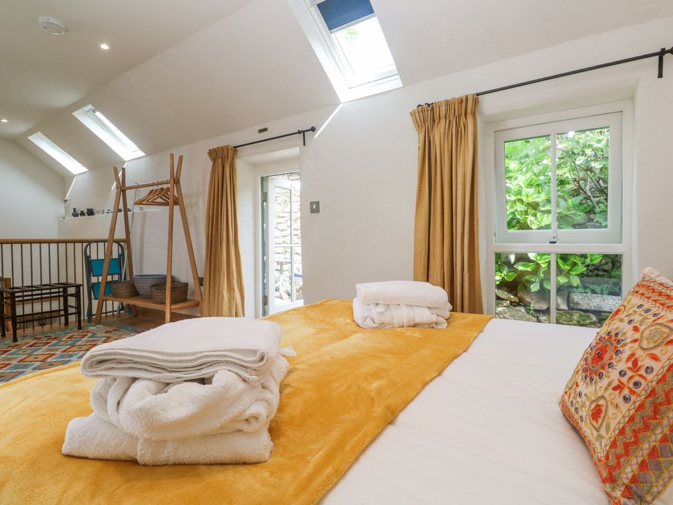 A bedroom with a bed and towels at The Stables in St Just