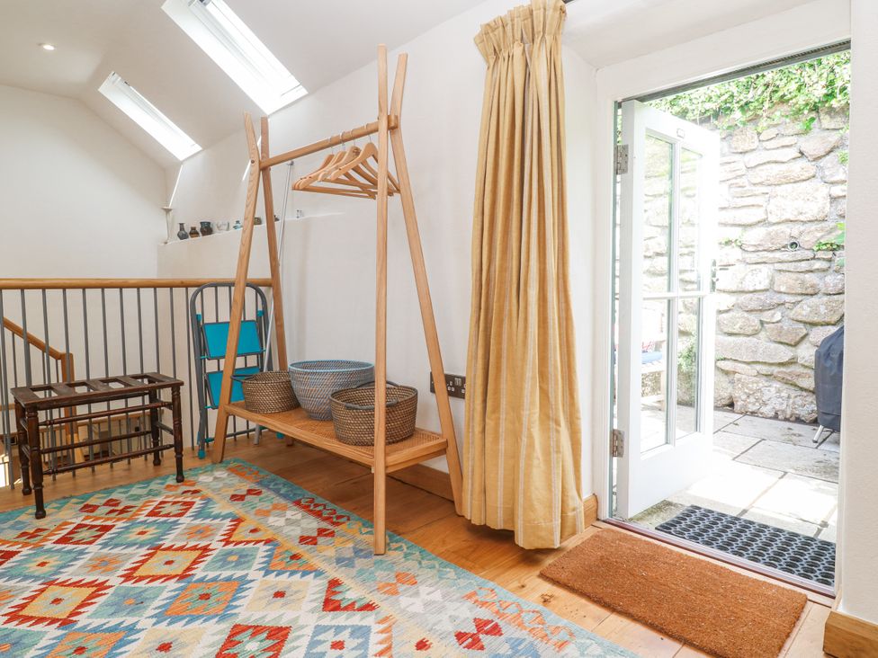 A hallway with coat rack and baskets at The Stables in St Just