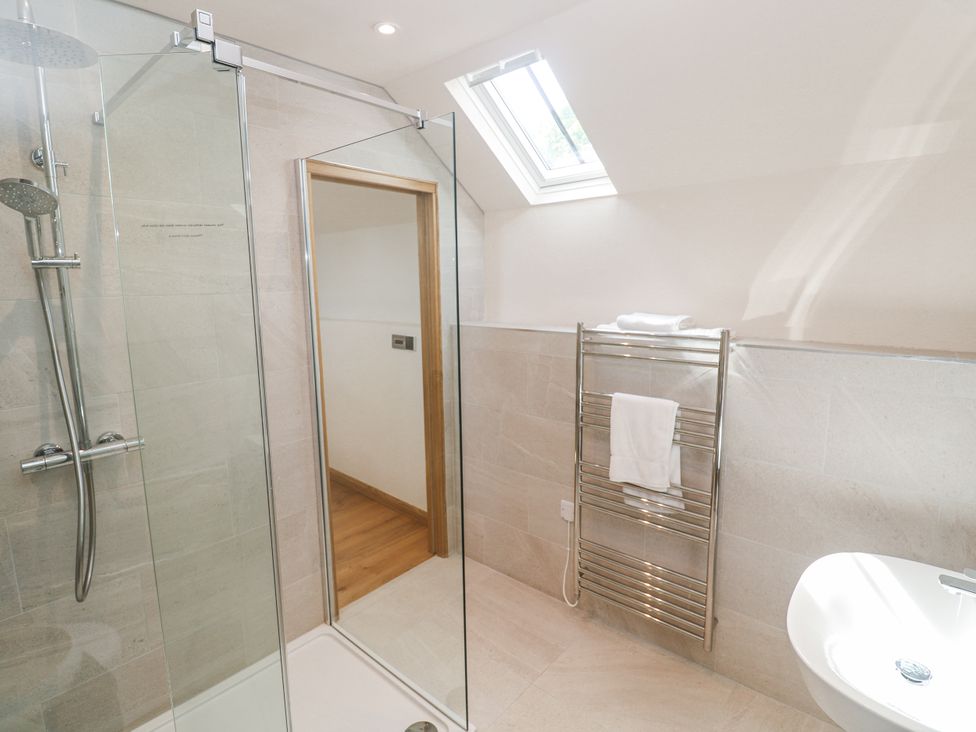 A bathroom with a shower, towel rack, and sink at The Stables in St Just