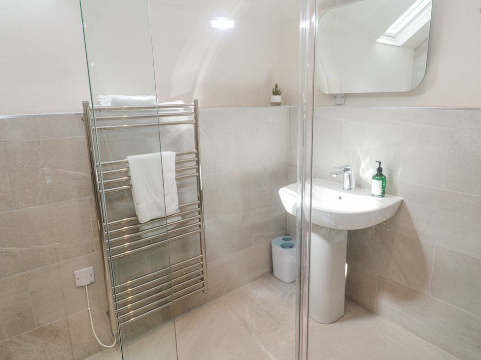 A bathroom with a shower, sink, toilet, and towel rail at The Stables in St Just
