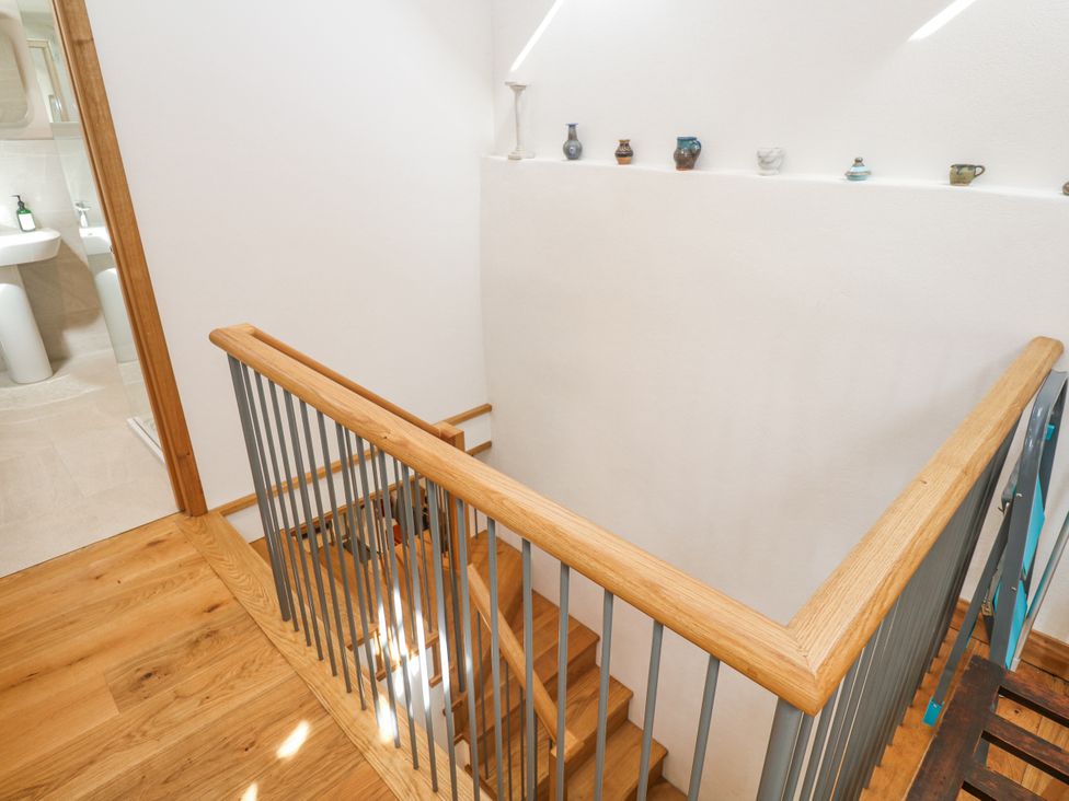 A staircase with railing and decorative objects in a hallway at The Stables in St Just