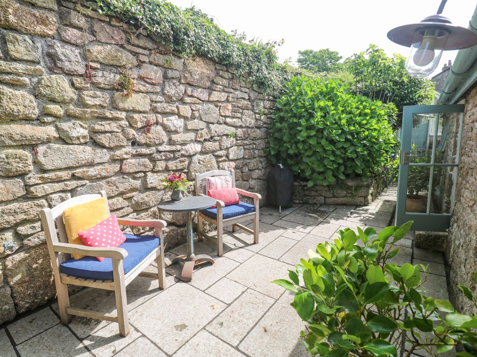 A patio area with chairs and a table surrounded by a stone wall at The Stables St Just