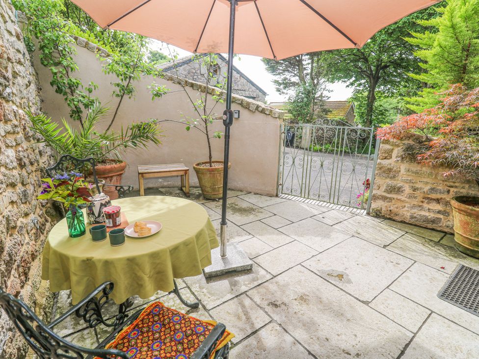 An outdoor area with a table under an umbrella at The Stables in St Just