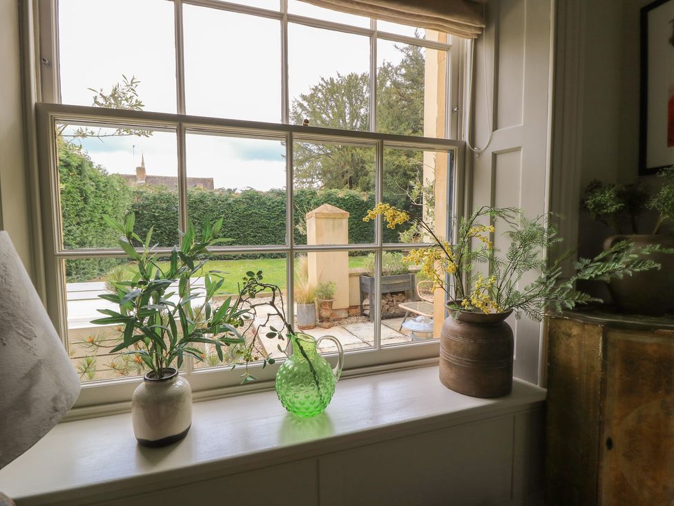 A window with plants and a view of the garden at Cotswold House in Moreton-In-Marsh