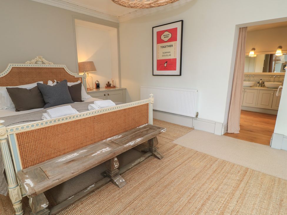 A bedroom with a bed and a doorway to an ensuite at Cotswold House in Moreton-In-Marsh