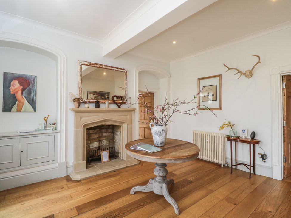 A living room with a fireplace and a table at Cotswold House in Moreton-In-Marsh