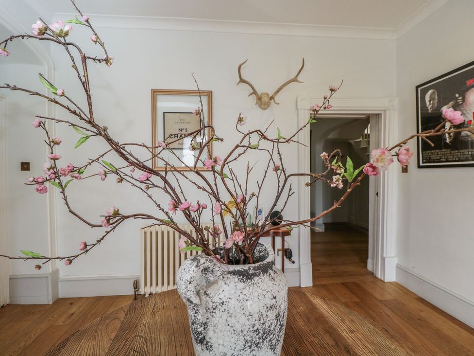 A living room with a vase containing branches and flowers at Cotswold House in Moreton-In-Marsh