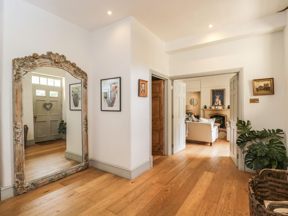 A hallway with a mirror and door at Cotswold House in Moreton-In-Marsh