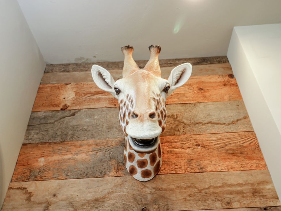 A giraffe head mounted on wooden paneling at Cotswold House in Moreton-In-Marsh