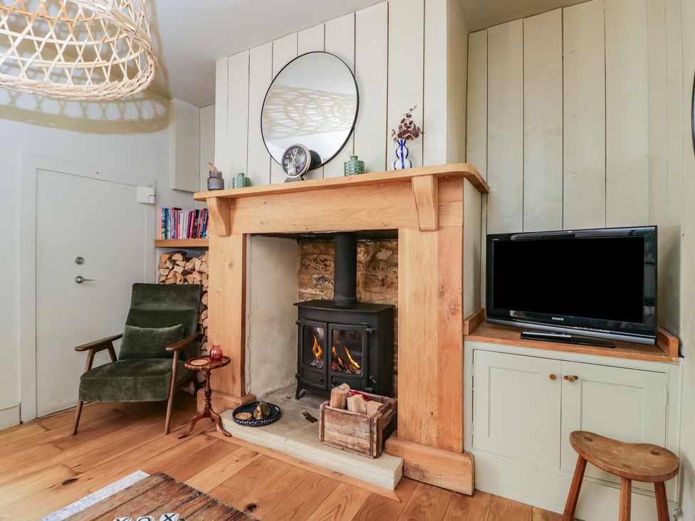A living room with a fireplace and television at Cotswold House in Moreton-In-Marsh
