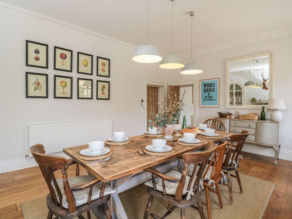 A dining room with a wooden table and eight chairs at Cotswold House in Moreton-In-Marsh