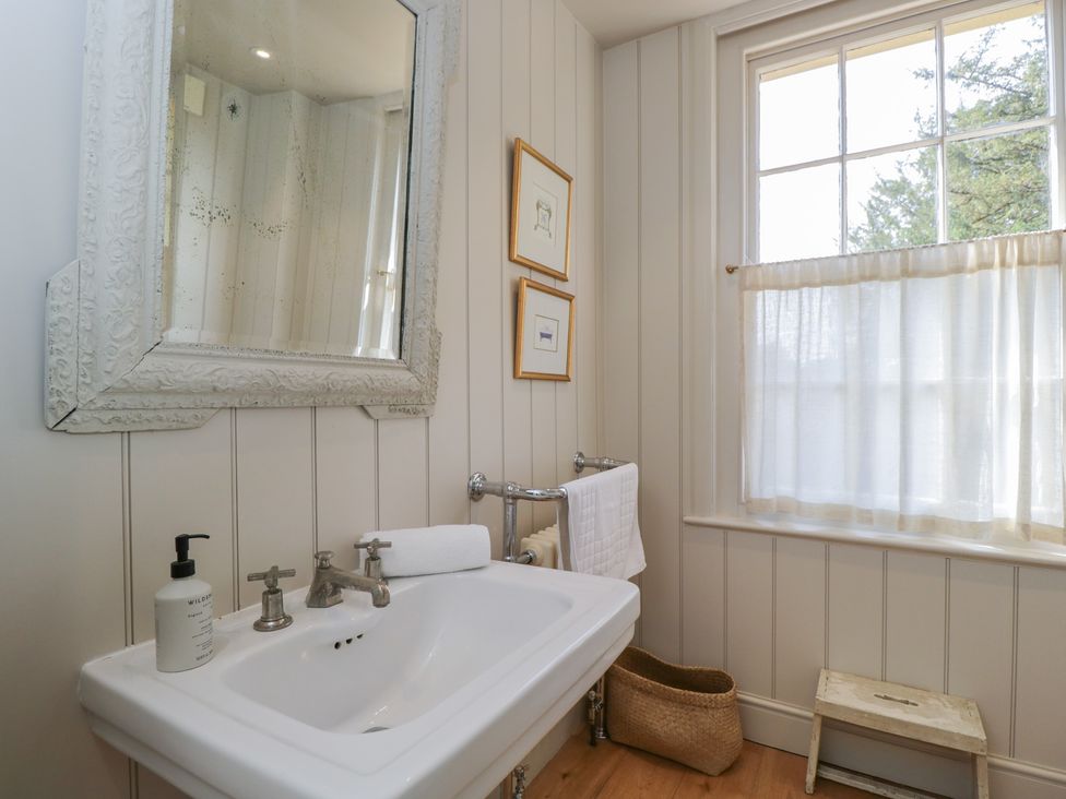 A bathroom with a sink, mirror and window at Cotswold House Moreton-In-Marsh