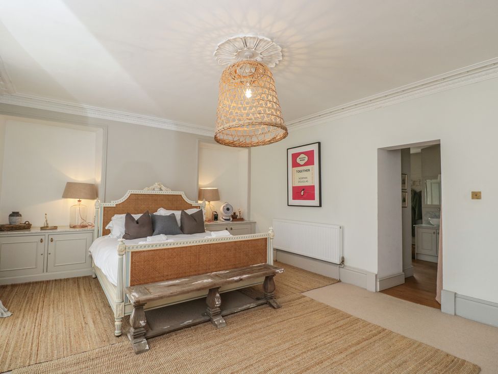 A bedroom with a bed, dresser, and lamp at Cotswold House in Moreton-In-Marsh