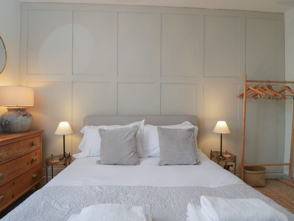 A bedroom with a bed, bedside lamps, and a dresser at Cotswold House in Moreton-In-Marsh