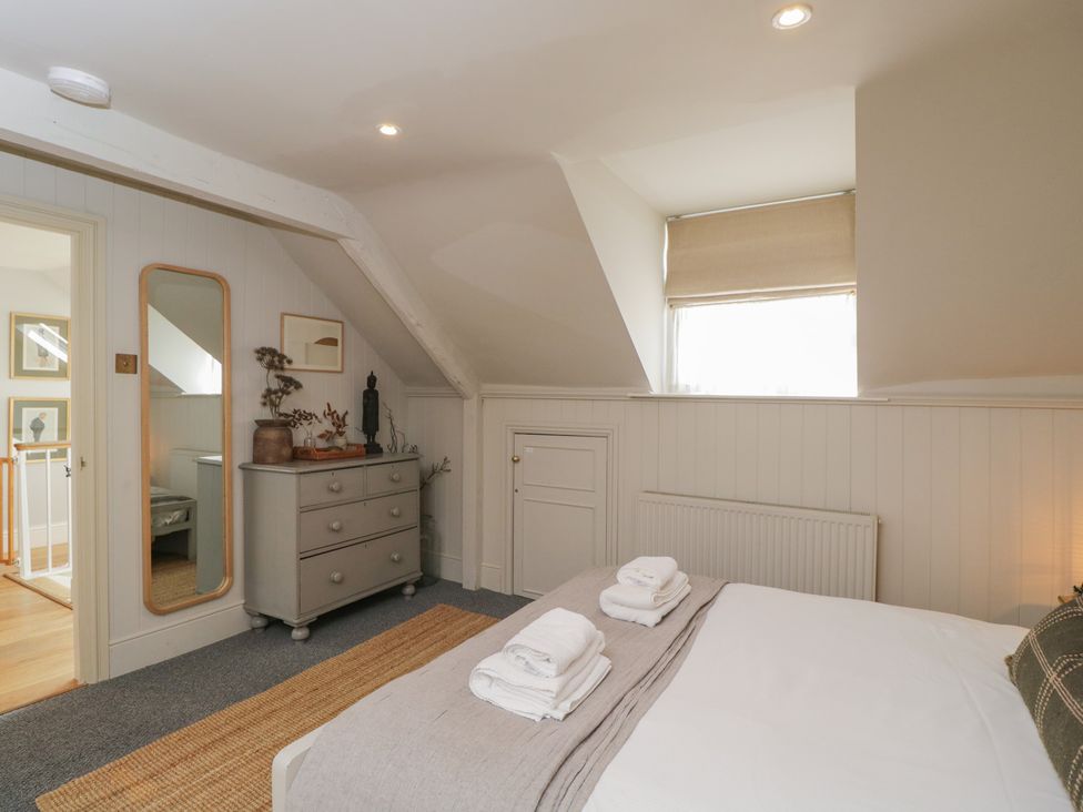 A bedroom with a bed, dresser, and mirror at Cotswold House in Moreton-In-Marsh