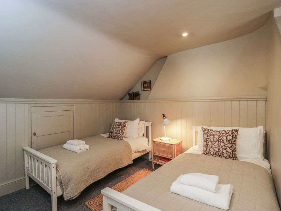 A bedroom with two beds and a lamp at Cotswold House in Moreton-In-Marsh