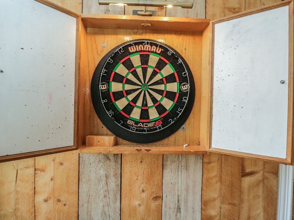 A dartboard mounted on a wooden cabinet in a game room at Cotswold House in Moreton-In-Marsh