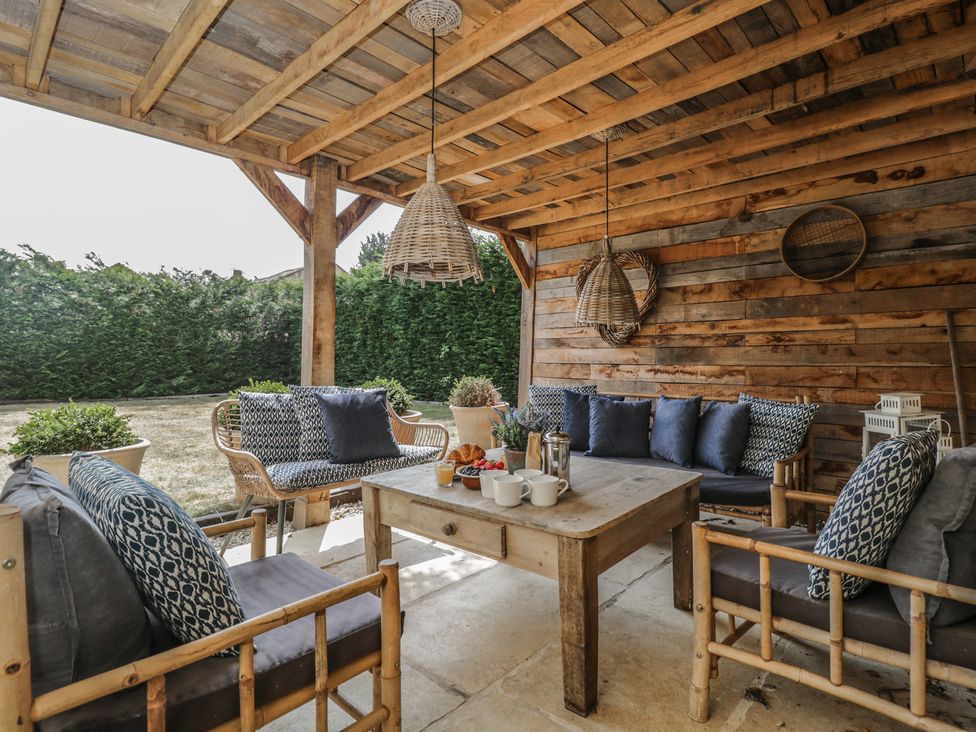 An outdoor covered patio with seating and a table at Cotswold House in Moreton-In-Marsh