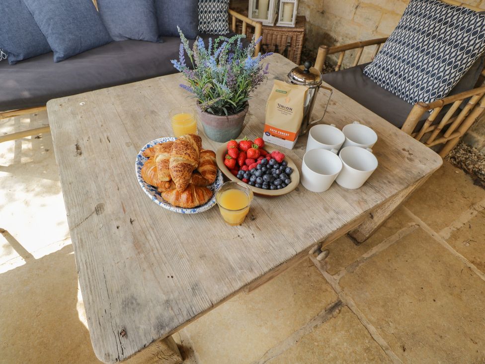 An outdoor seating area with a table set with croissants, fruits, and drinks at Cotswold House in Moreton-In-Marsh
