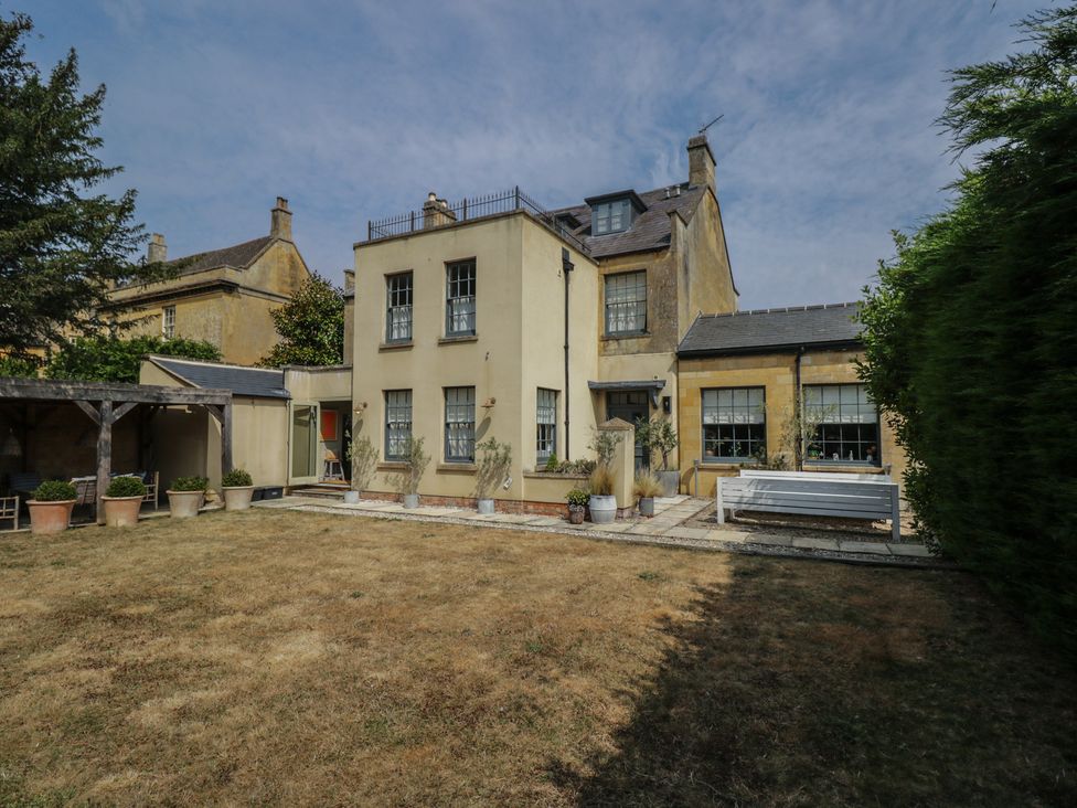A garden with a house and planters at Cotswold House in Moreton-In-Marsh