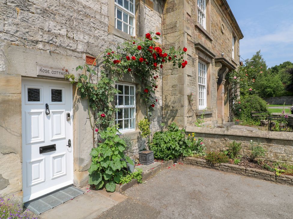 An entrance with flowers and signage at Rose Cottage in Hartington