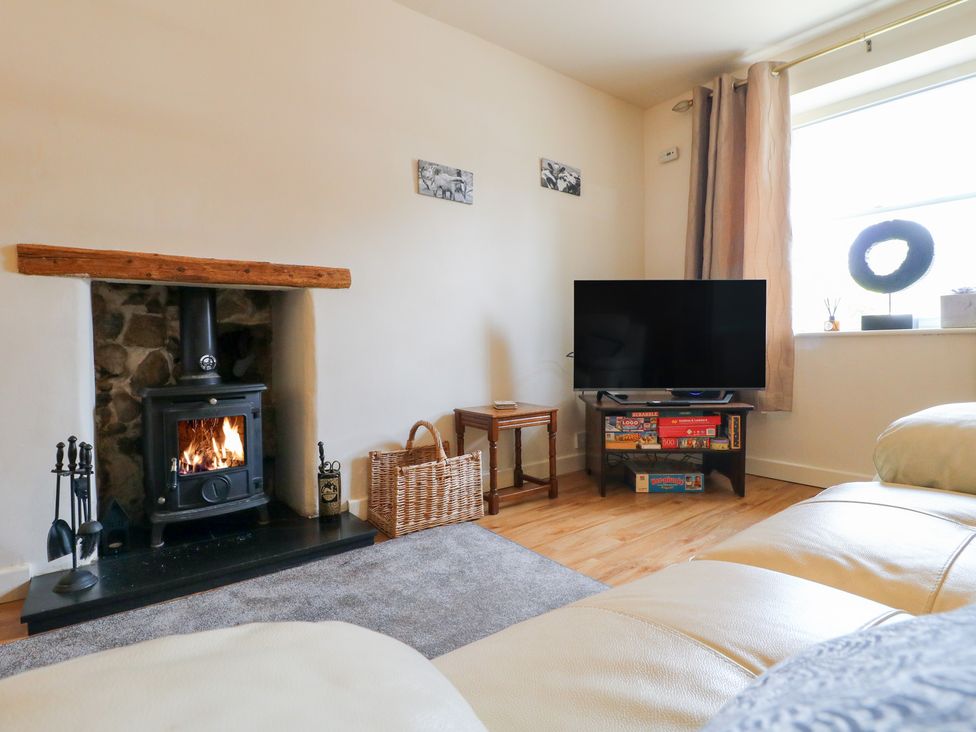 A living room with a fireplace and television at Rose Cottage in Hartington