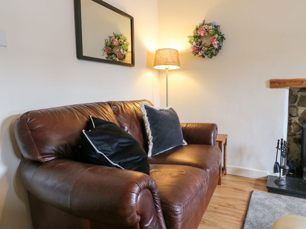 A living room with a sofa, lamp, and mirror at Rose Cottage Hartington