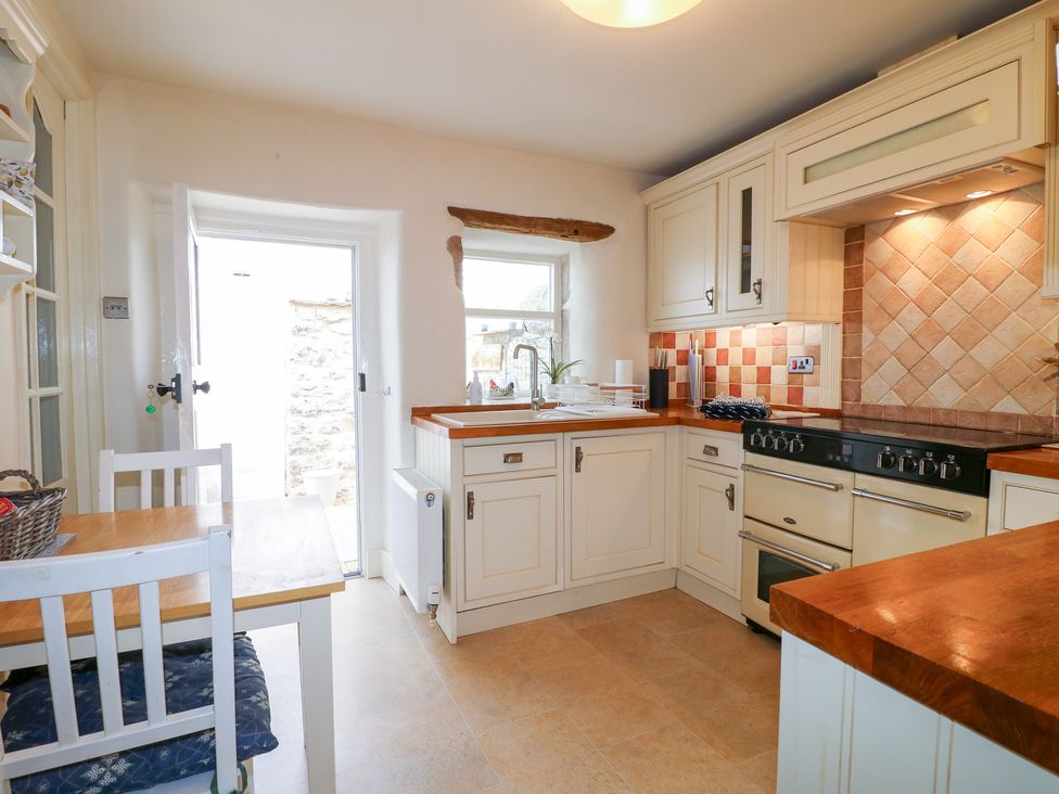 A kitchen with cabinets, a stove, and a dining table at Rose Cottage in Hartington