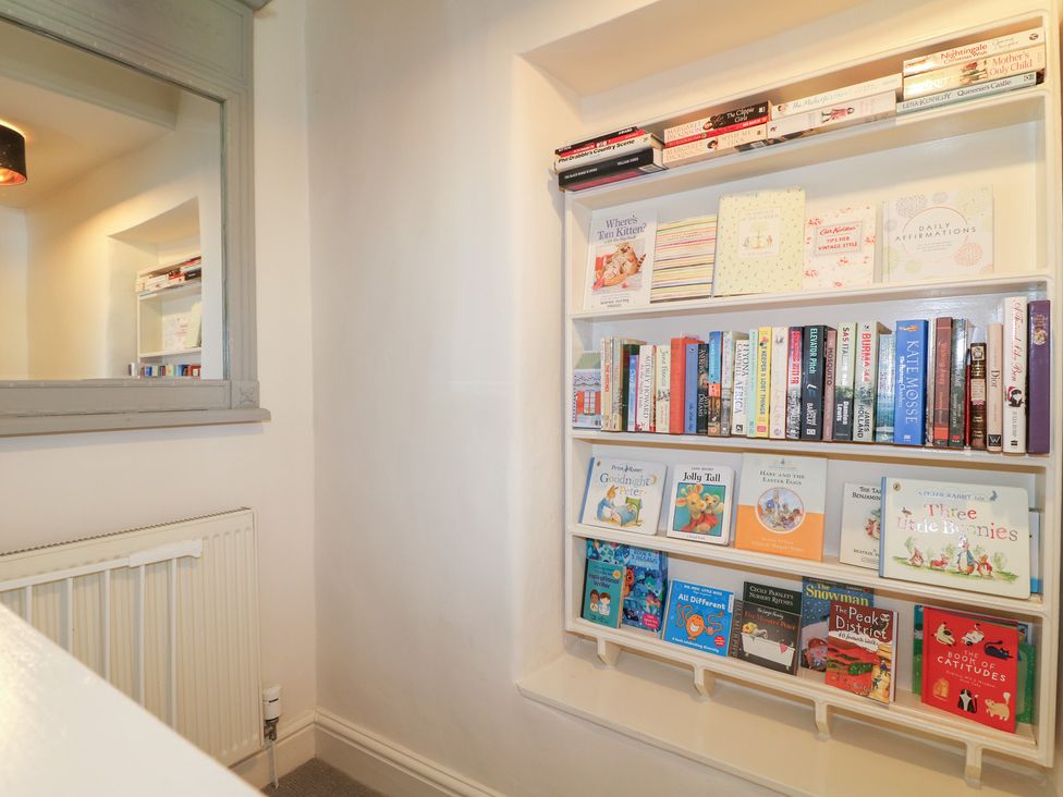 A reading area with a bookshelf and a radiator at Rose Cottage in Hartington
